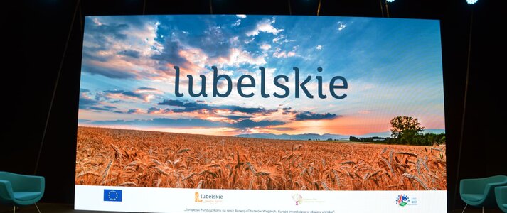 Plansza do webinarium przedstawiająca pole dojrzałego zboża oraz zachód słońca. Na środku planszy napis Lubelskie, a na dole logotypy PROW 2014-2020, KSOW, Lubelskie smakuj życie oraz flagę Unii Europejskiej
