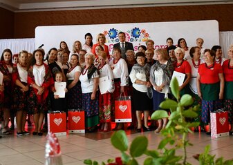 Duża grupa osób stoi ustawiona do wspólnego zdjęcia w dużej Sali w restauracji. Są to kobiety z kół gospodyń wiejskich biorące udział w konkursie „Kobieta Przedsiębiorcza”. Niektóre z nich trzymają w dłoniach czerwone torebki prezentowe w sercem z białych literek „L” będących znakiem województwa lubelskiego. Wśród nich jest pani Ewa Szałachwiej, Dyrektor Departamentu Rolnictwa i Rozwoju Obszarów Wiejskich oraz starosta powiatu parczewskiego.