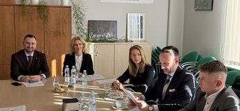 Uczestnicy spotkania Grupy Tematycznej do spraw chmielu siedzą przy stole konferencyjnym, na którym rozłożone są materiały dotyczące omawianych zagadnień