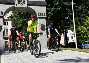 Rowerzyści przejeżdżają przez łuk triumfalny. Jest to start rajdu