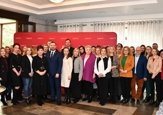 Uczestnicy konferencji stoją w sali na tle ścianki promocyjnej województwa lubelskiego