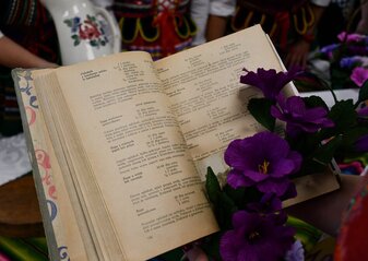 Rozłożona stara książka kucharska trzymana w dłoniach