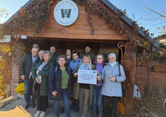 Grupa uczestników stojąca przed drewnianym budynkiem z szyldem Winnica Widokowa Komboria