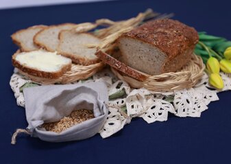 Chleb wiejski w koszyczkach, obok dekoracja: ziarna zboża w lnianym woreczku oraz tulipany