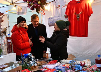 Pan zdisław szwed Członek zarzadu Wojeództwa Lubelskiego wraz z Panią Ewą Szałachwiej rozmawiają z wystawcą przy stoisku na jarmarku Bożonarodzeniowym
