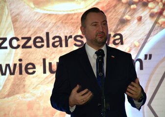 Wicemarszałek Marek Wojciechowski mówi do mikrofonu podczas konferencji „Wsparcie pszczelarstwa w województwie lubelskim. Jest to ujęcie pokazujące sylwetkę do pasa