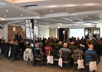 Duża grupa osób siedząca tyłem w Sali konferencyjnej