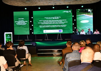 Uczestnicy konferencji „Wsparcie rozwoju sportu, rekreacji i turystyki na obszarach wiejskich województwa lubelskiego w ramach Planu Strategicznego dla Wspólnej Polityki Rolnej na lata 2023–2027 – LEADER” siedzą na Sali konferencyjnej i oglądają prezentację przedstawiającą dobre praktyki.