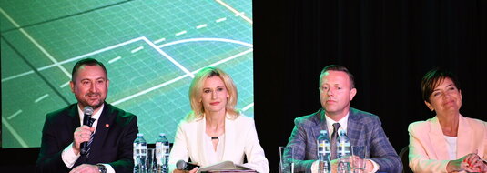 Za stołem prezydialnym podczas konferencji „Wsparcie rozwoju sportu, rekreacji i turystyki na obszarach wiejskich województwa lubelskiego w ramach Planu Strategicznego dla Wspólnej Polityki Rolnej na lata 2023–2027 – LEADER”, siedzą cztery osoby: od lewej strony wicemarszałek województwa lubelskiego Marek Wojciechowski, dyrektor Departamentu Rolnictwa i Rozwoju Obszarów Wiejskich Urzędu Marszałkowskiego Województwa Lubelskiego w Lublinie - Ewa Szałachwiej, radny województwa lubelskiego Michał Mulawa i zastępca dyrektora Departamentu Rolnictwa i Rozwoju Obszarów Wiejskich Urzędu Marszałkowskiego Województwa Lubelskiego w Lublinie – Dorota Kozak. Do uczestników konferencji przez mikrofon mówi wicemarszałek Marek Wojciechowski.