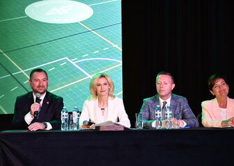 Za stołem prezydialnym podczas konferencji „Wsparcie rozwoju sportu, rekreacji i turystyki na obszarach wiejskich województwa lubelskiego w ramach Planu Strategicznego dla Wspólnej Polityki Rolnej na lata 2023–2027 – LEADER”, siedzą cztery osoby: od lewej strony wicemarszałek województwa lubelskiego Marek Wojciechowski, dyrektor Departamentu Rolnictwa i Rozwoju Obszarów Wiejskich Urzędu Marszałkowskiego Województwa Lubelskiego w Lublinie - Ewa Szałachwiej, radny województwa lubelskiego Michał Mulawa i zastępca dyrektora Departamentu Rolnictwa i Rozwoju Obszarów Wiejskich Urzędu Marszałkowskiego Województwa Lubelskiego w Lublinie – Dorota Kozak. Do uczestników konferencji przez mikrofon mówi wicemarszałek Marek Wojciechowski.