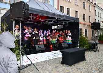 Na scenie występuje zespół ludowy. Scena stoi na Starym Mieście w Lublinie podczas Jarmarku Bożonarodzeniowego