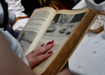 Stara książka kucharska trzymana w dłoniach przez kobietę