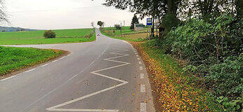 skrzyżowanie nowych dróg pomiędzy polami wraz z przystankiem autobusowym pod drzewem