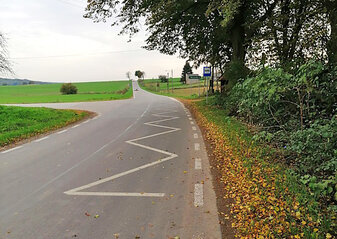 skrzyżowanie nowych dróg pomiędzy polami wraz z przystankiem autobusowym pod drzewem