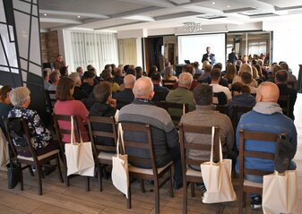 Duża grupa osób siedząca tyłem w Sali konferencyjnej
