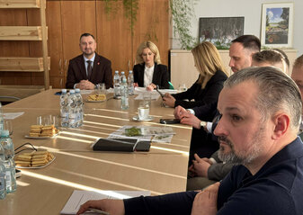 Uczestnicy spotkania Grupy Tematycznej do spraw chmielu siedzą przy stole konferencyjnym, na którym rozłożone są materiały dotyczące omawianych zagadnień