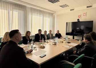 Uczestnicy spotkania Grupy Tematycznej do spraw chmielu siedzą przy stole konferencyjnym, na którym rozłożone są materiały dotyczące omawianych zagadnień